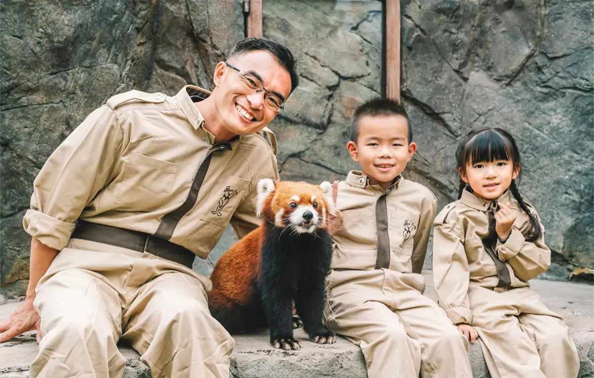 A family posing with a red panda at an animal park